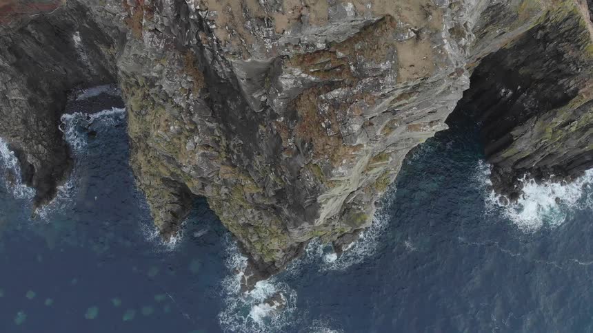 Ocean waves crash into a rocky cliff on the coast