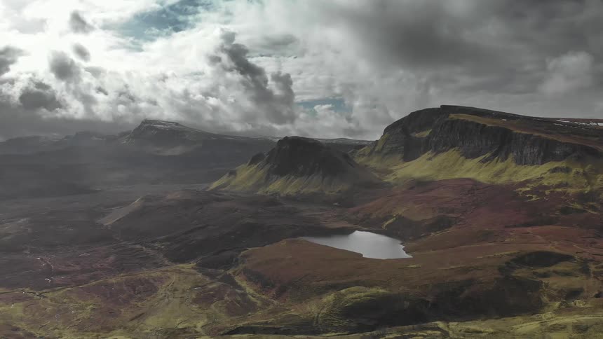 A pond with mountains and the sky in the background