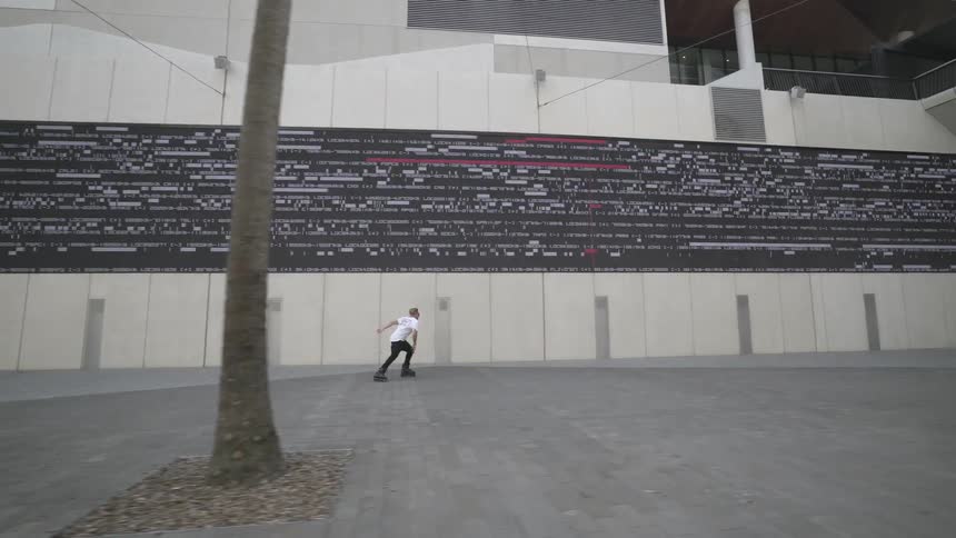 Man moves along the ground using roller skates next to the big building