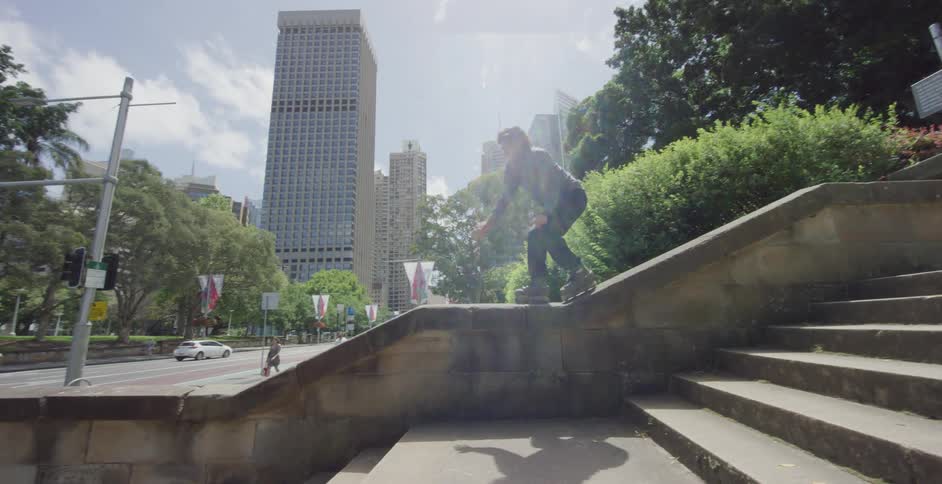 A man with inline skates skating and jumping down a concrete staircase railing
