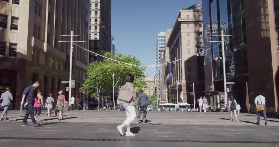 Pedestrians cross courtyard between buildings on clear day