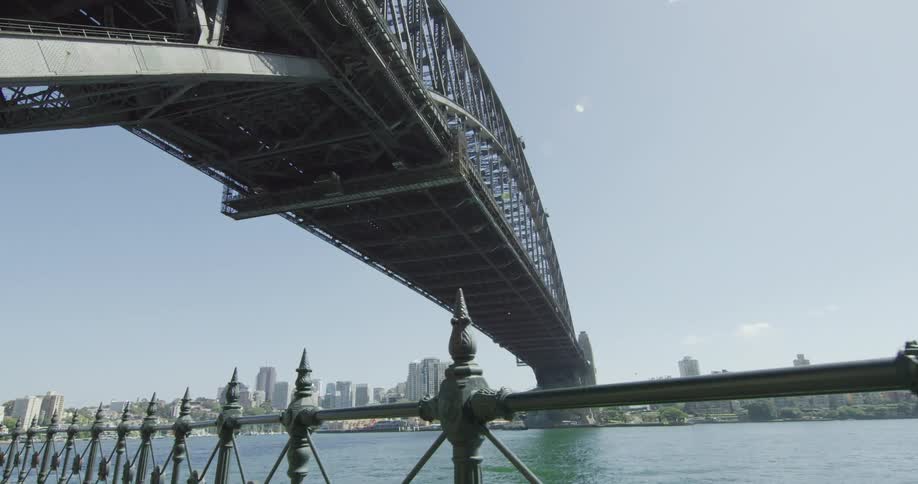A bridge looms over a river flowing by a city