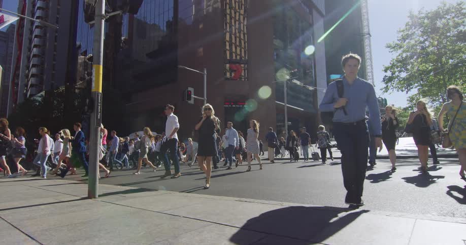 Crowd of pedestrians cross the street near building