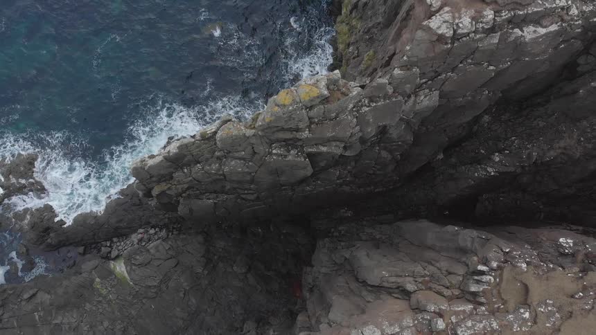 Aerial shot of water hitting a cliff