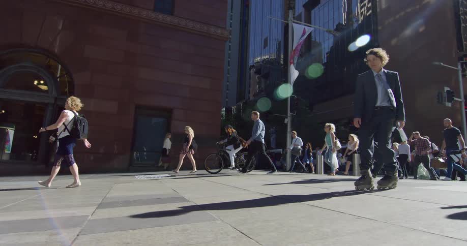 A teenager in a suit roller blades through a busy public area with many people walking