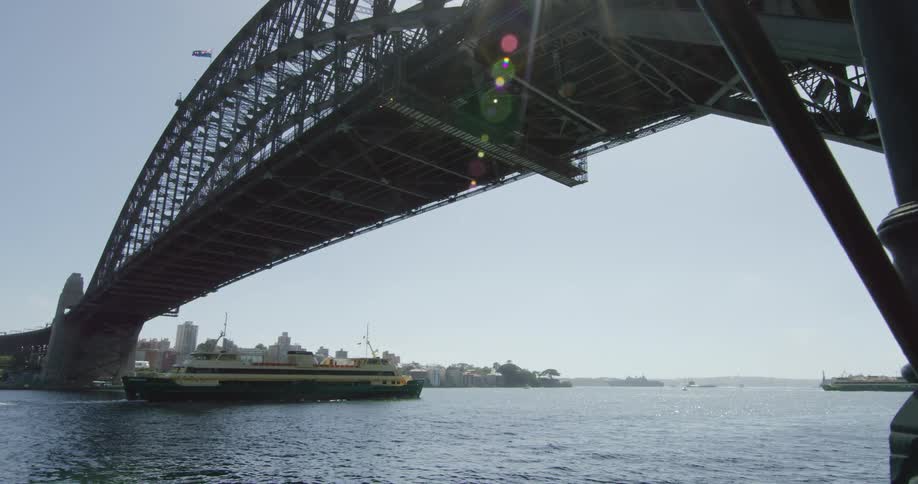 A large ship passing under a bridge outside of a city