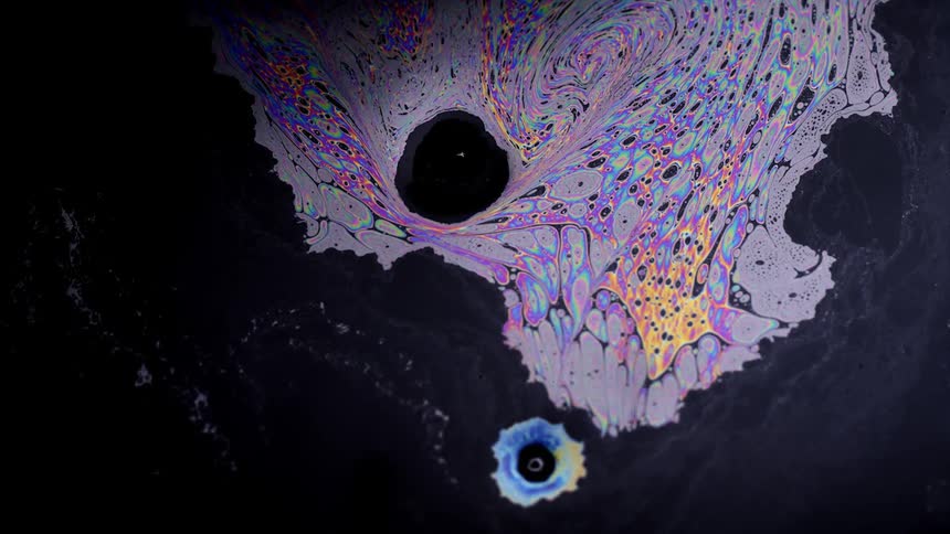 Colorful digital texture swirls merges and emerges against a black textured background