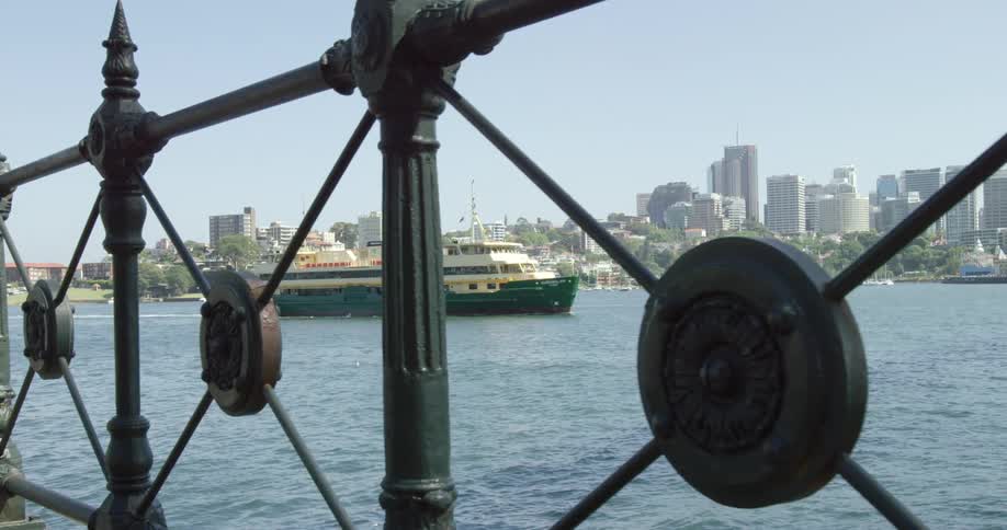 A ferry boat is navigating across a harbor in a metropolitan area during the day