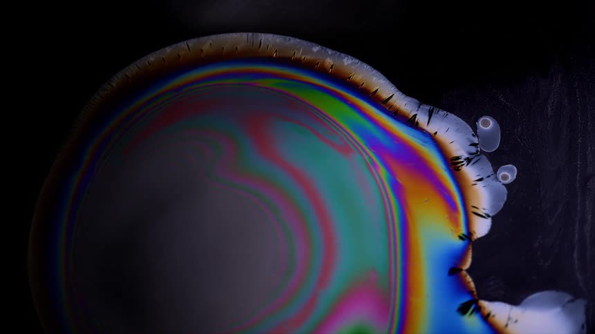 A colorful liquid expands with a black liquid background