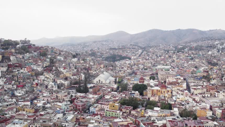 Houses and buildings are built close together and fill nearly all space near a mountain range