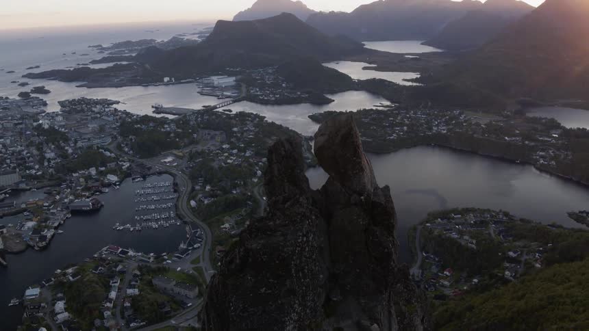 A rocky cliff with a Norwegian coastal town in the background