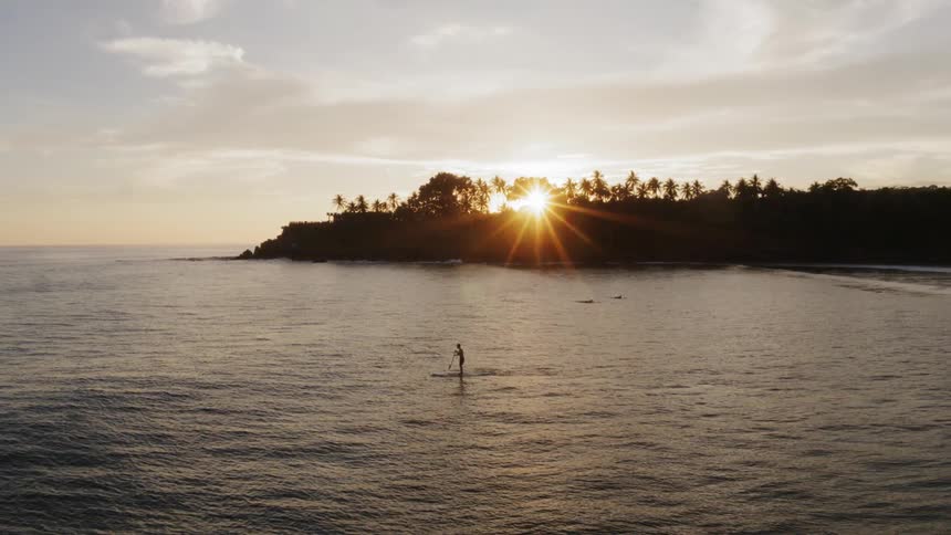 A person paddles across the ocean