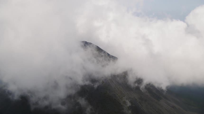 Clouds obscure the peak of a volcano