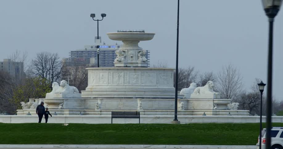 An adult and child walk around a city monument structure