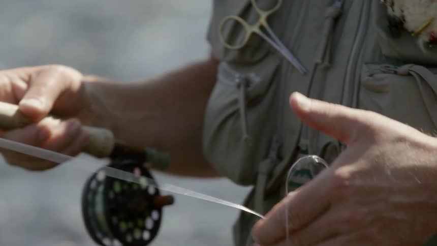 A fisherman adjusts the fishing line before casting