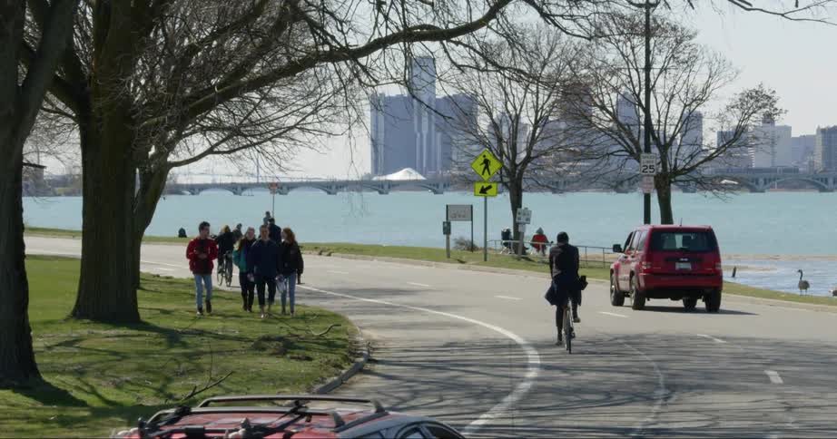 Cars people and cyclists move along a road