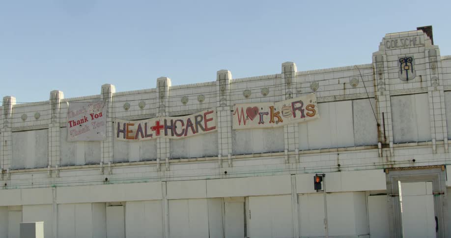 Banners and signs for healthcare workers hang on the side of a city building