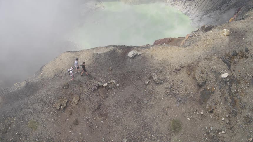 Hikers walk along the rim of a volcano