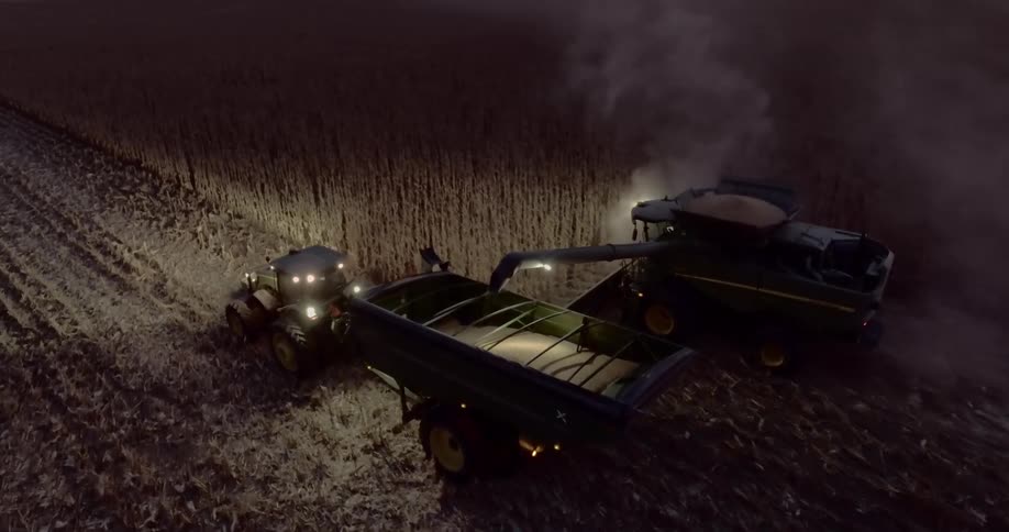 Two tractors driving in a field harvesting wheat