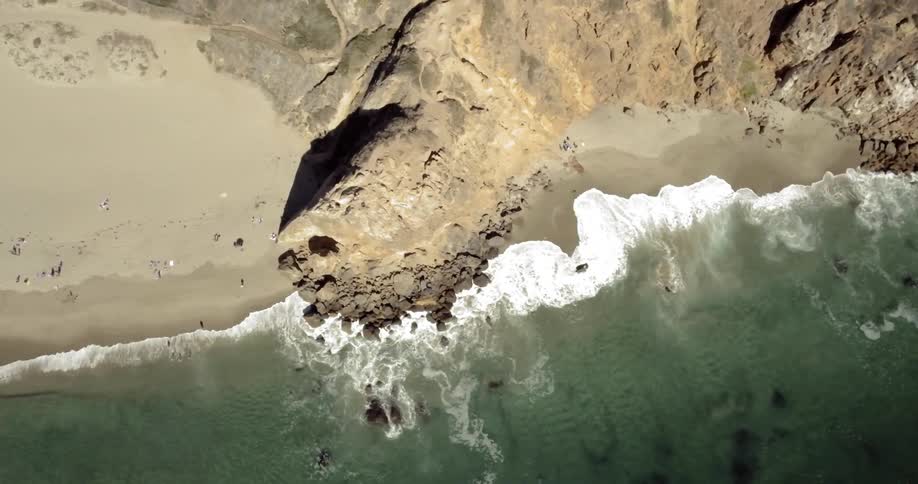 Birds eye view of people on a beach as waves roll in to shore