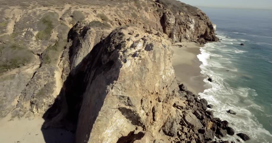 Aerial view of men and women standing on the edge of the cliff