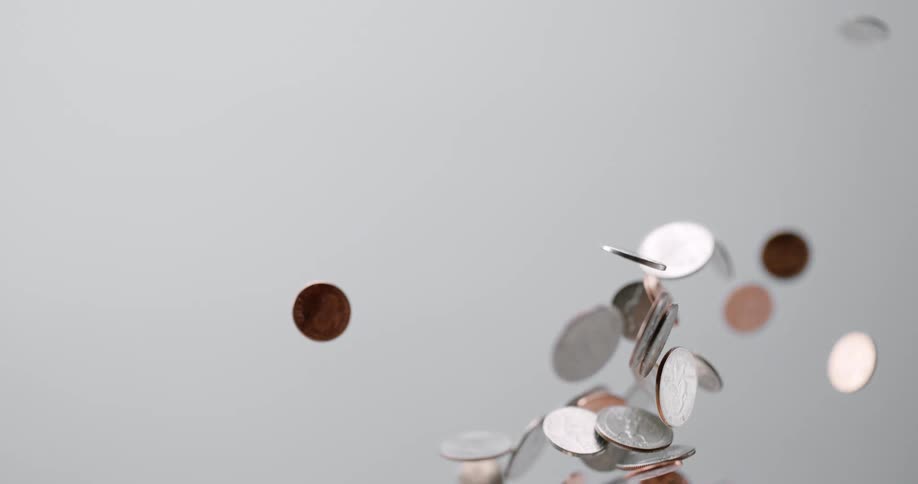 Coins being tossed up and falling down with a white background