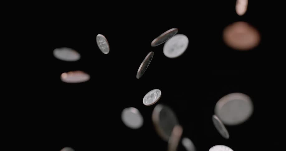 Coins are tossed up in the air and fall back down against a black backdrop