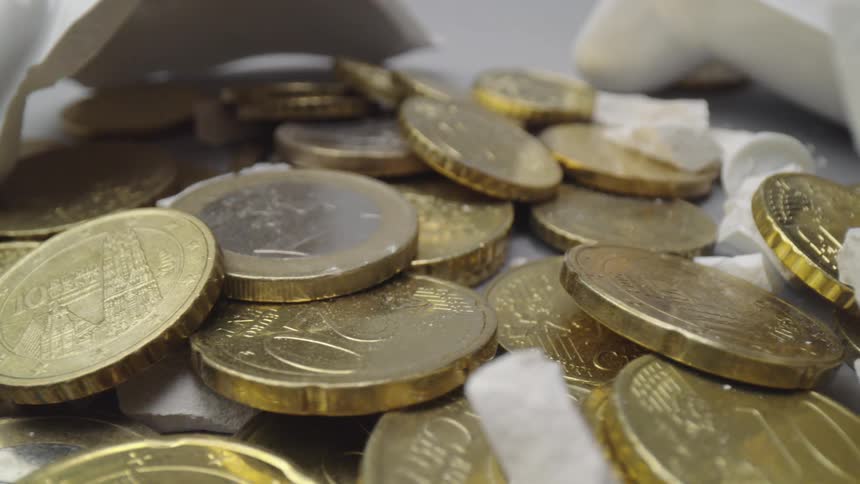 A broken piggy bank with coins in the middle