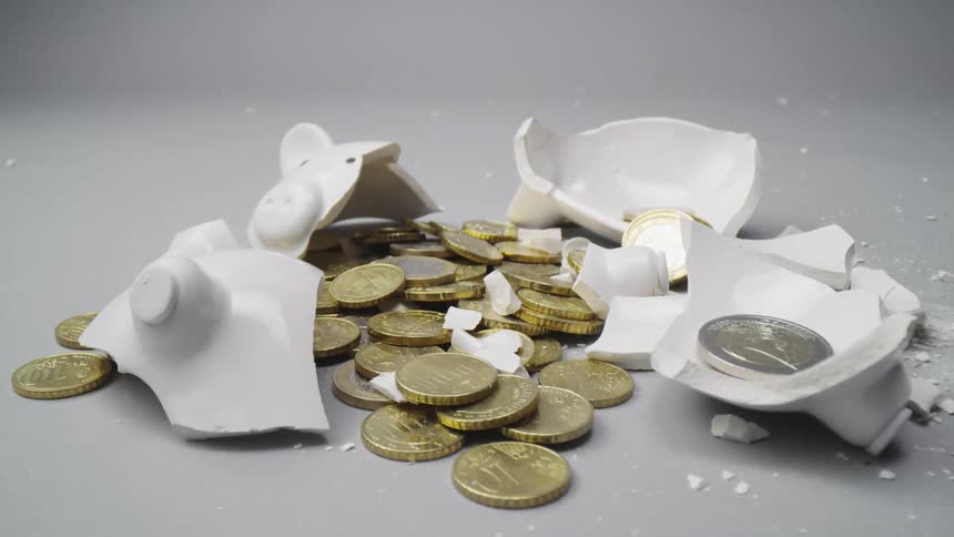 Gold coins sit piled up around a broken piggy bank