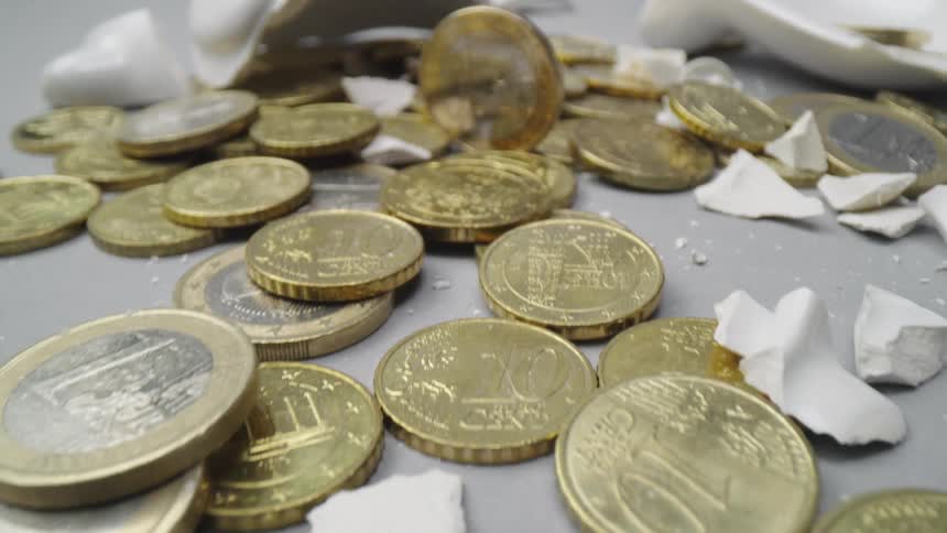 Gold coins lay scattered among the broken pieces of a shattered ceramic piggy bank