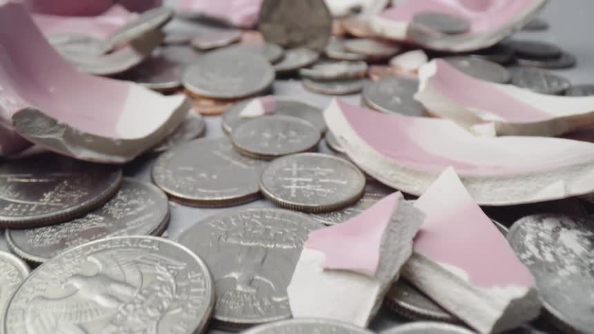 Coins scattered around pieces of broken piggy bank