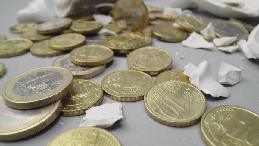 A piggy bank broken showing its contents of gold coins