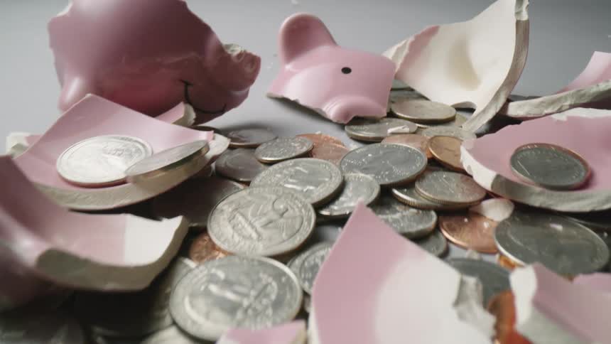 Change and the smashed pieces of a piggy bank sit on a gray surface