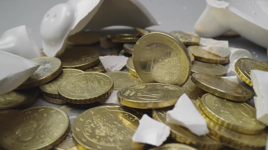 Cluster of gold coins lay among broken pieces of white ceramic piggy bank