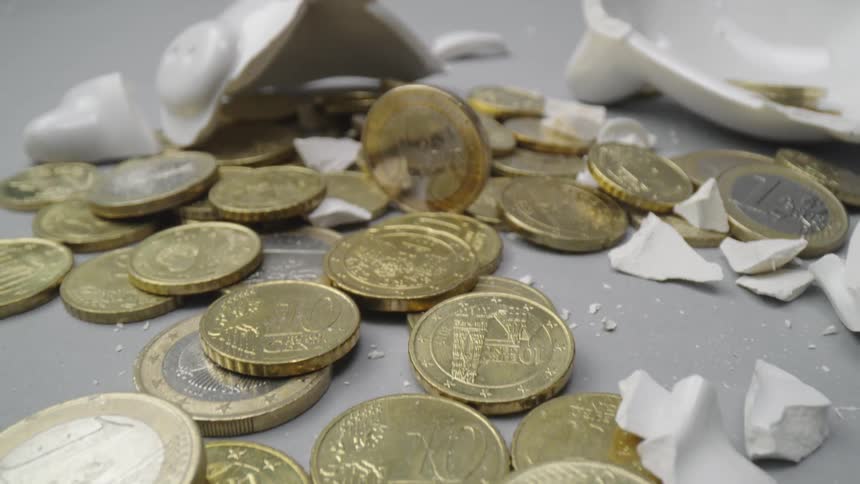 Coins sit outside a broken piggy bank