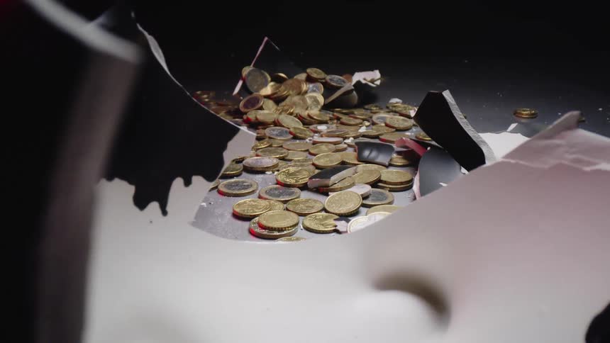 Shot of a broken piggy bank with coins all over