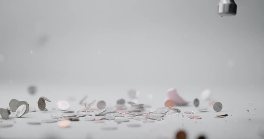 A person smashing a pink piggy bank with a hammer