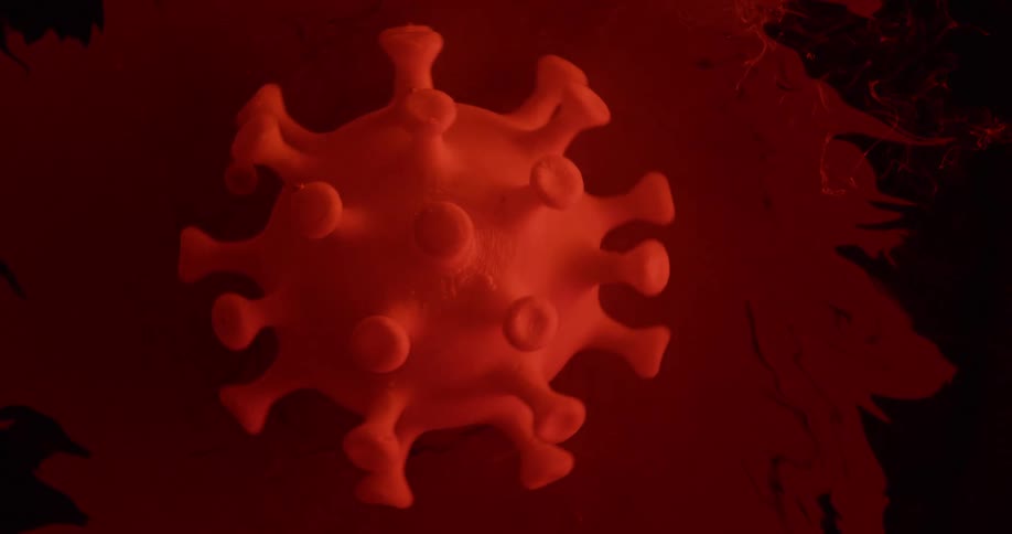 A replica of a virus turning in red and black liquid