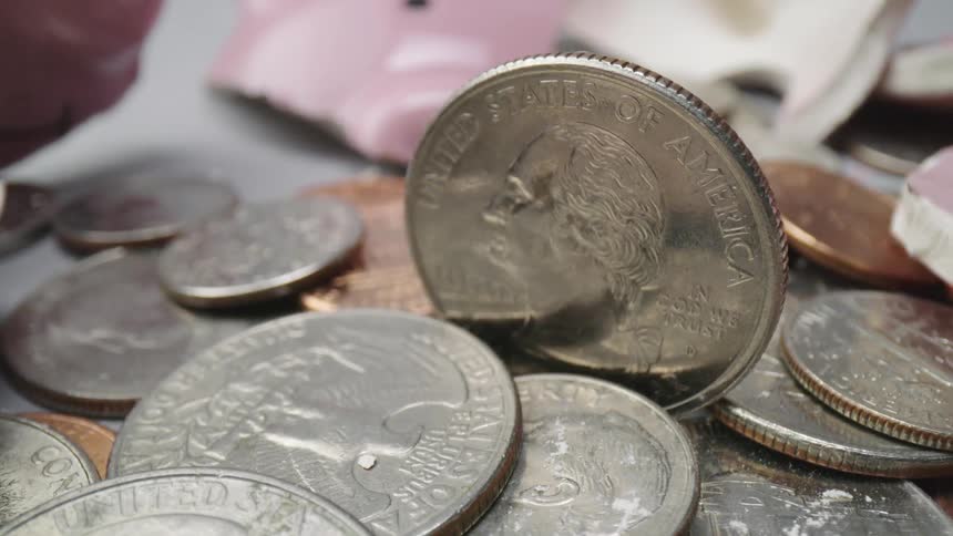 A quarter stands on its edge with other coins