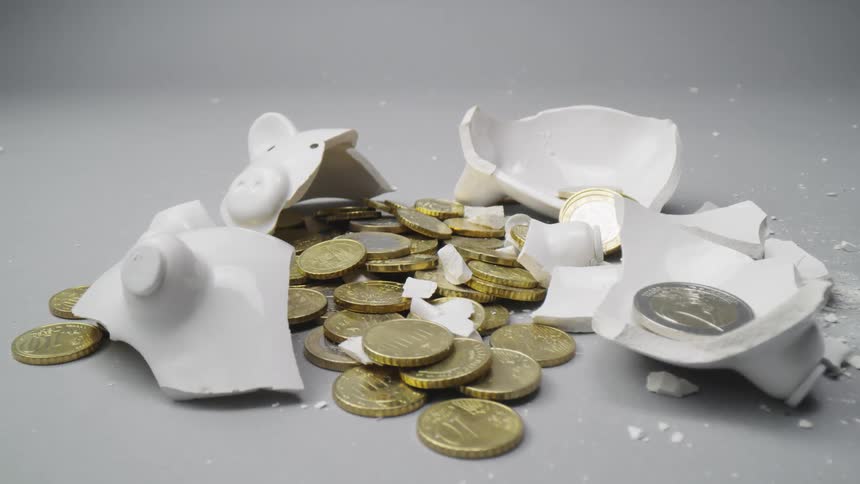 A broken white piggy bank with coins in the middle