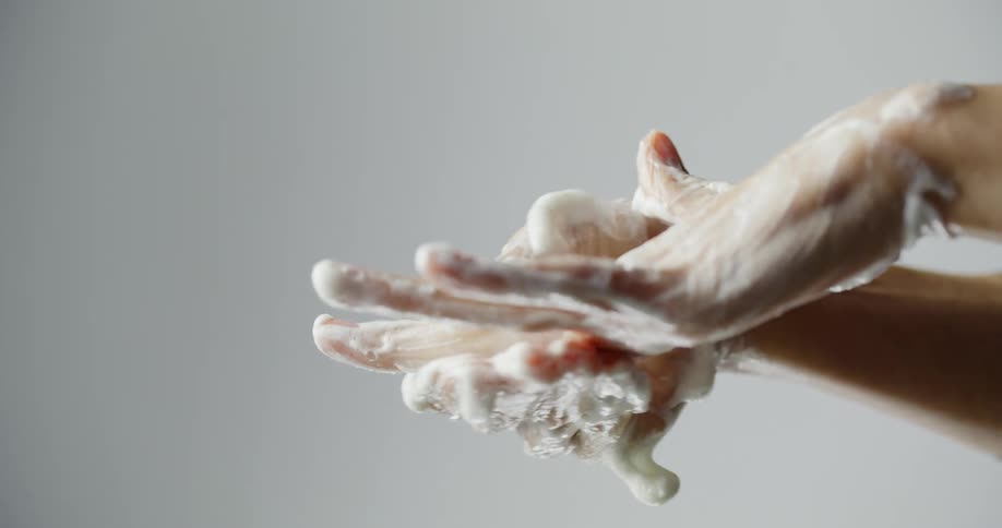 A person thoroughly washing their hands with soap and scrubbing each finger