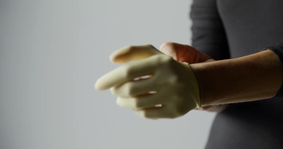 A woman puts a glove on her hand