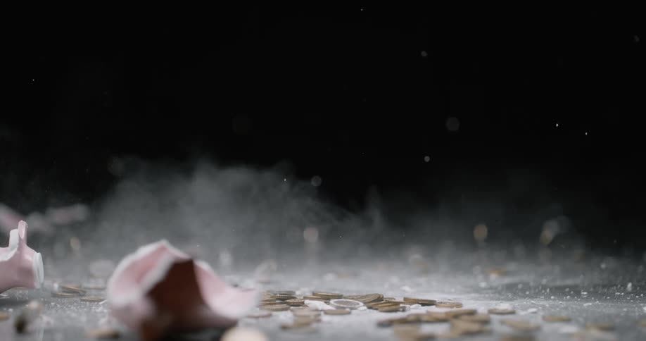 A hammer smashes a piggy bank filled with coins