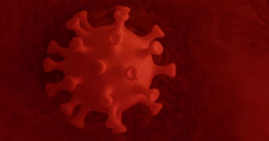 A replica of a corona virus turning in red liquid