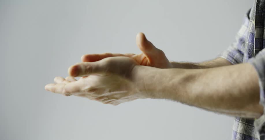 A man sprays his hands with sanitizer and then rubs them together