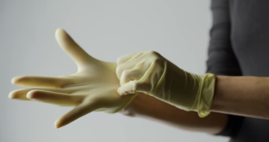 A woman puts on a pair of yellow latex gloves
