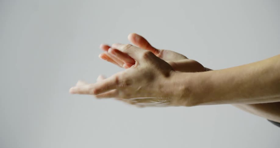 A person spraying hand sanitizer on their hands then rubbing their hands together