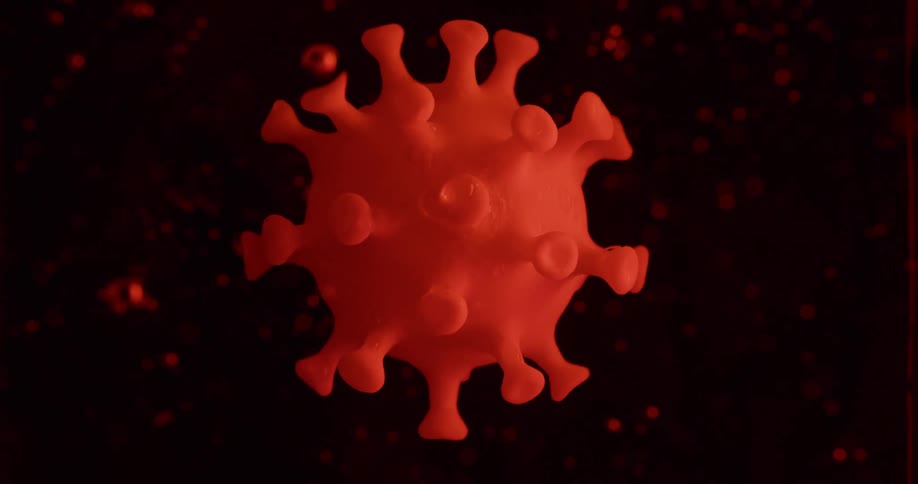 A red liquid with bubbles with a plastic replica of a virus