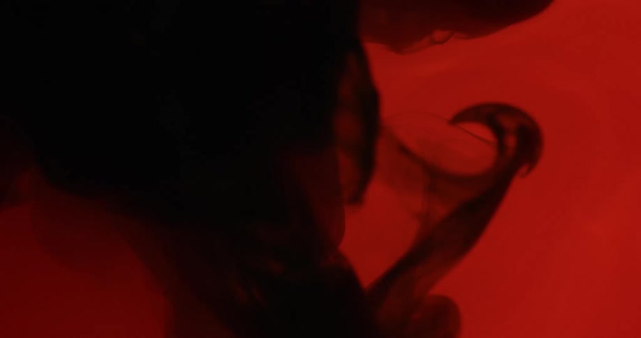Black liquid water falls down in the red background