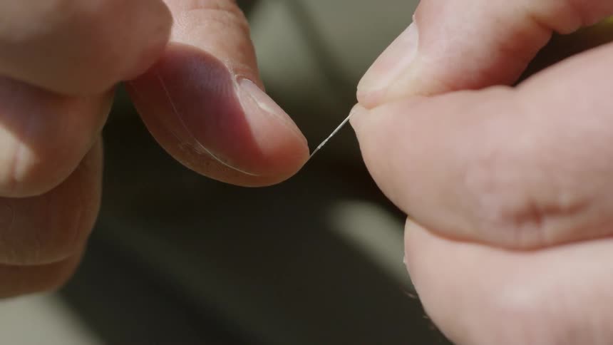 Fishing line is being tied into knots by fingers